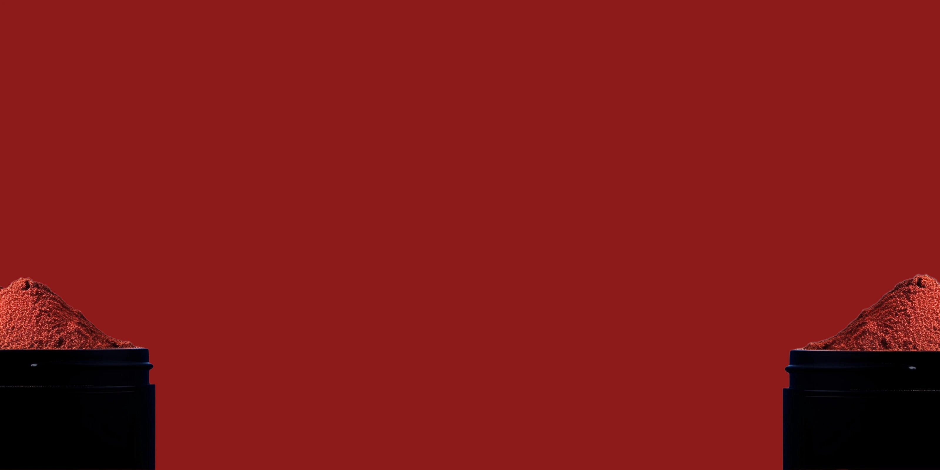 Image d'un mélange d'épices en poudre dans un pot noir en métal coupé en deux avec un fond rouge