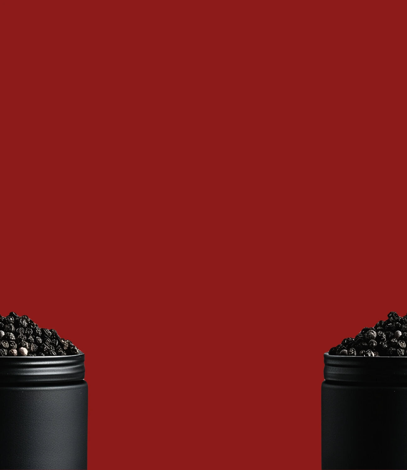 Image de grains de poivre de Madagascar dans un pot noir en métal coupé en deux avec un fond rouge