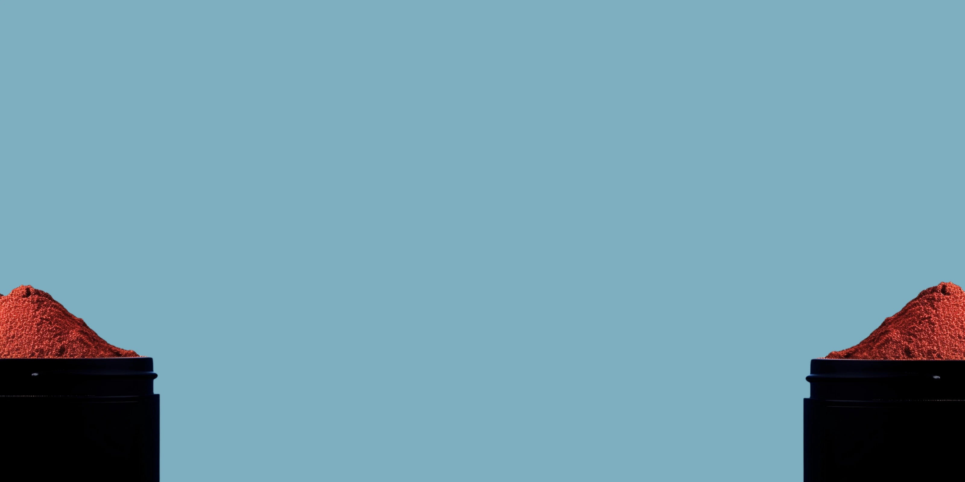 Image d'un mélange d'épices en poudre dans un pot noir en métal coupé en deux avec un fond bleu