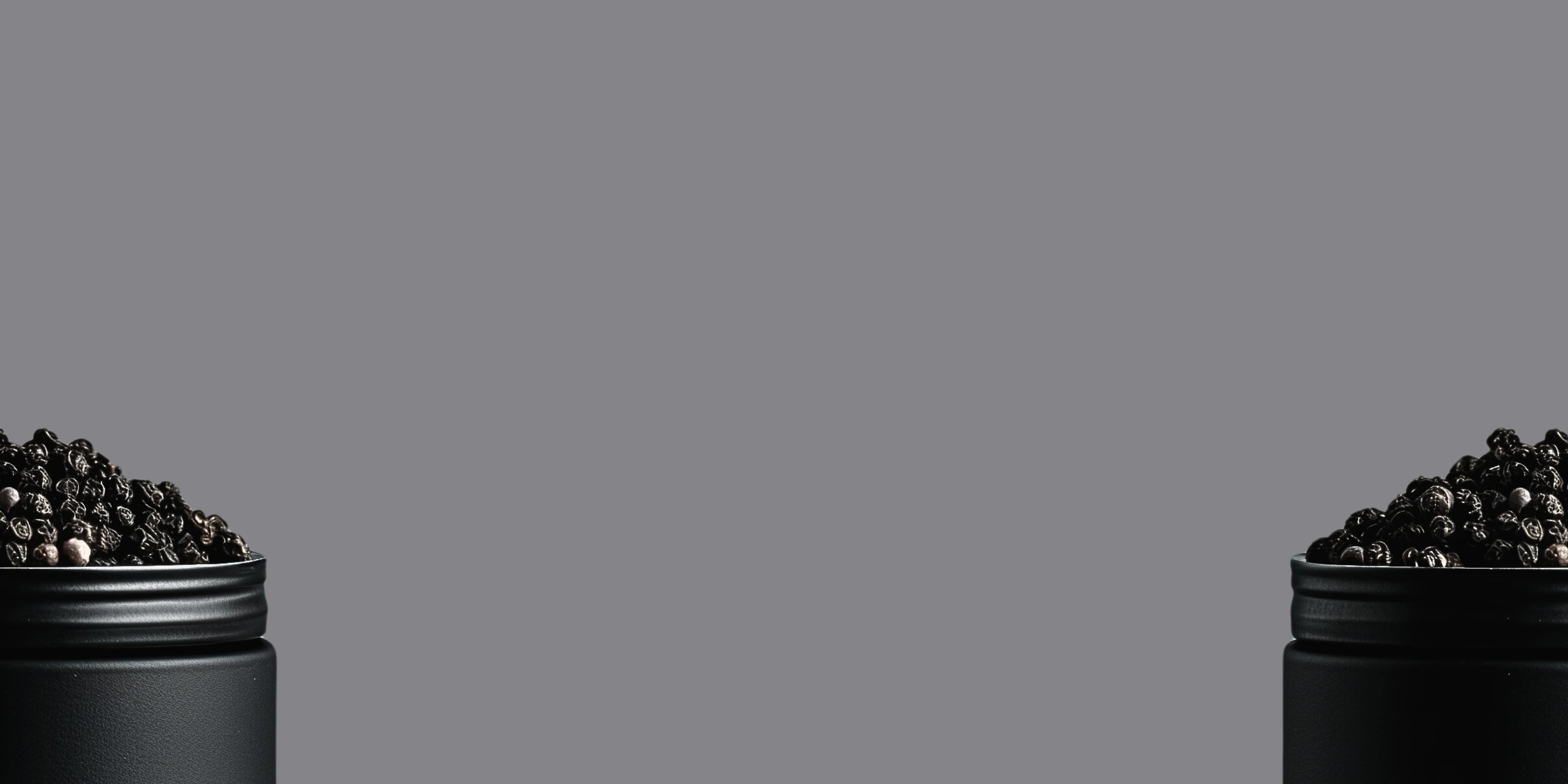 Image de grains de poivre de Madagascar dans un pot noir en métal coupé en deux avec un fond gris